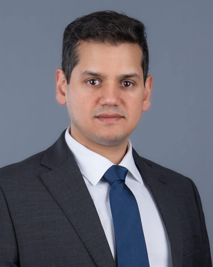 Young Ottawa Business headshot of man in grey suit blue tie on a grey background
