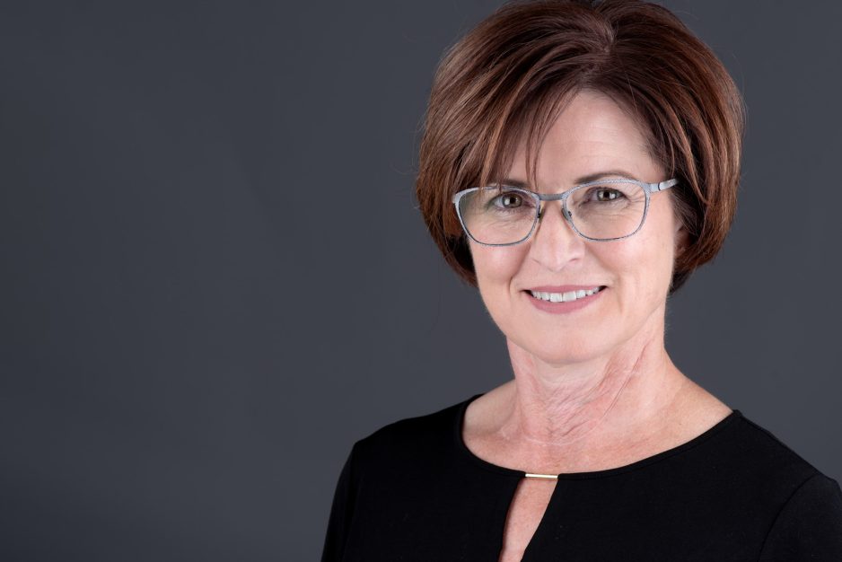 Professional woman headshot looking professional and wearing glasses on a grey background