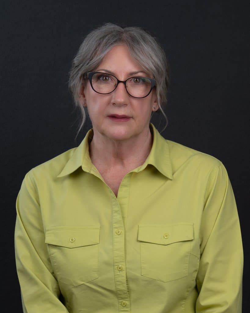 Grey haired Ottawa business woman with round glasses and a lime coloured top