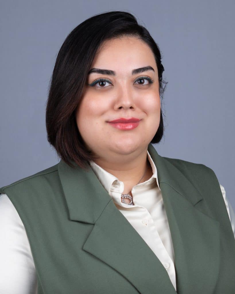 Young woman business headshot green vest white top on grey background