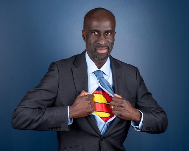 Man in a business suit with a Superman shirt underneath