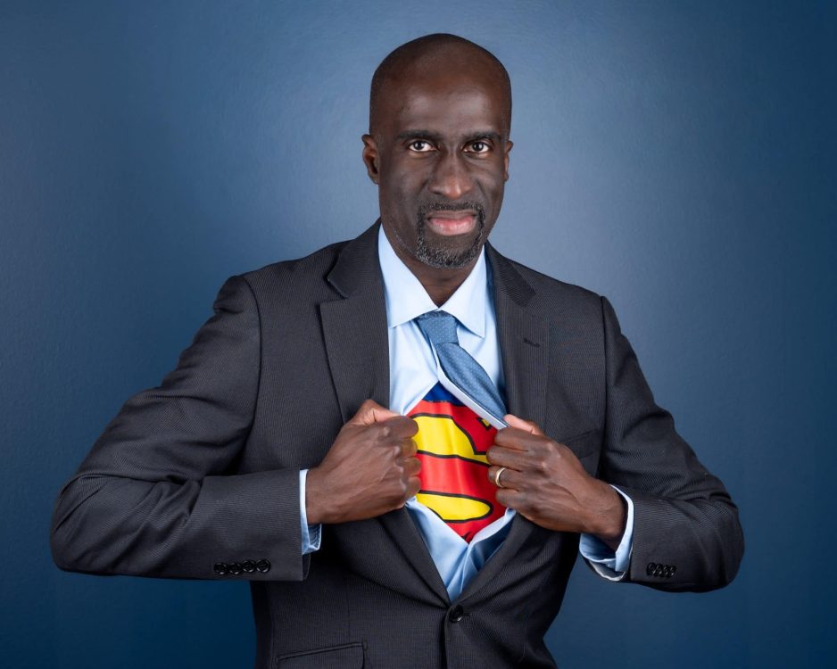 Man in a business suit with a Superman shirt underneath