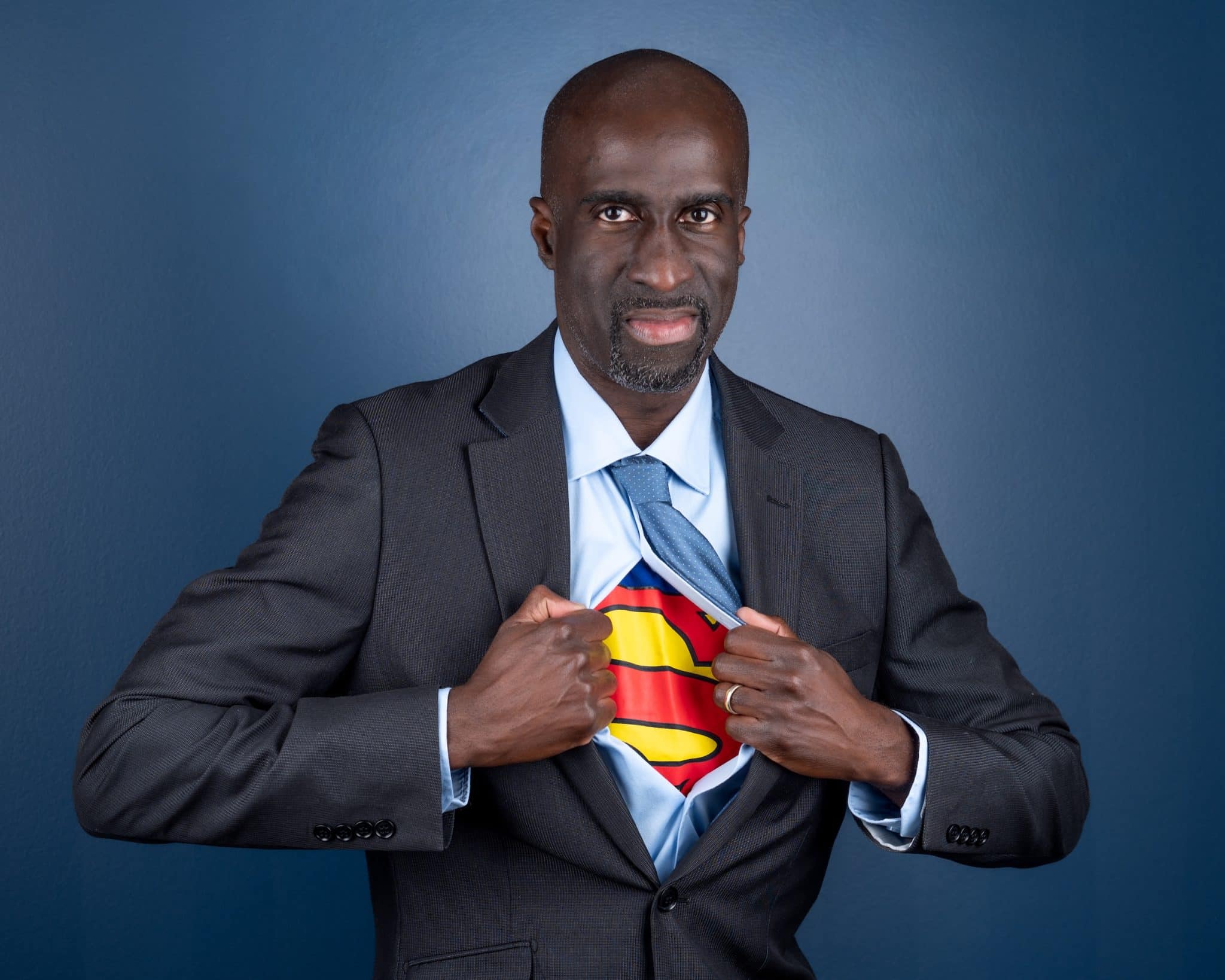 Man in a business suit with a Superman shirt underneath